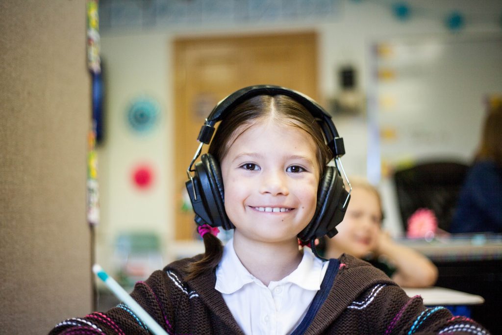 Menina criança sorrindo para a câmera enquanto recebe uma aula nos moldes da disciplina positiva.