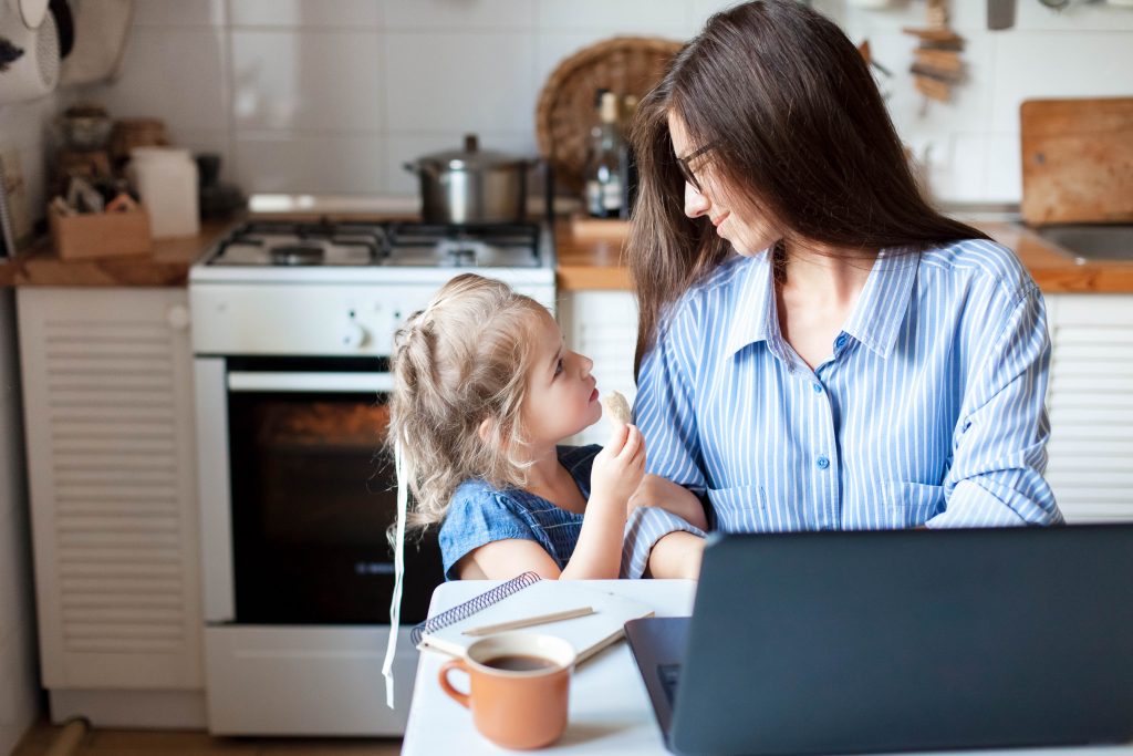 Mulher trabalhando na cozinha ao lado da filha.