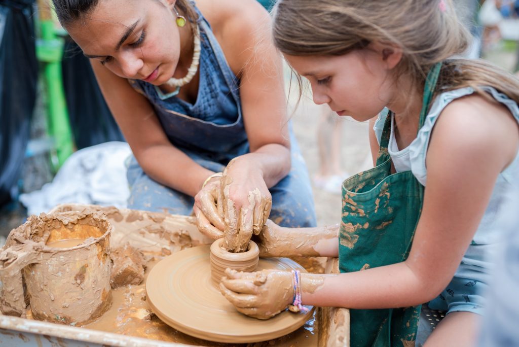Criança e mulher adulta brincando com argila, representando a importância da educação criativa.