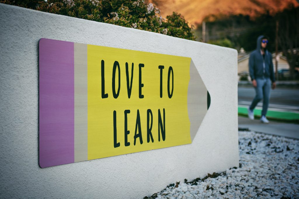 Placa em formato de lápis com os dizeres "love to learn" representando a educação criativa.